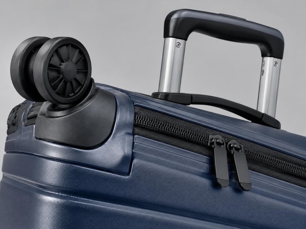 Close-up of a suitcase spinner wheel, handle and zipper